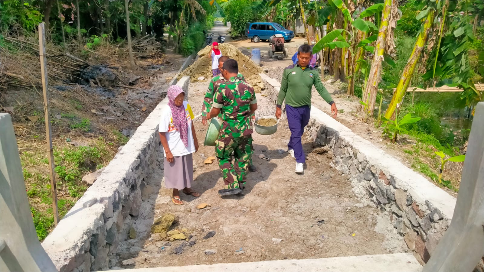 Ibu-Ibu Desa Burikan Turun Tangan Ratakan Urug Jalan Menuju Jembatan Garuda Bersama TNI